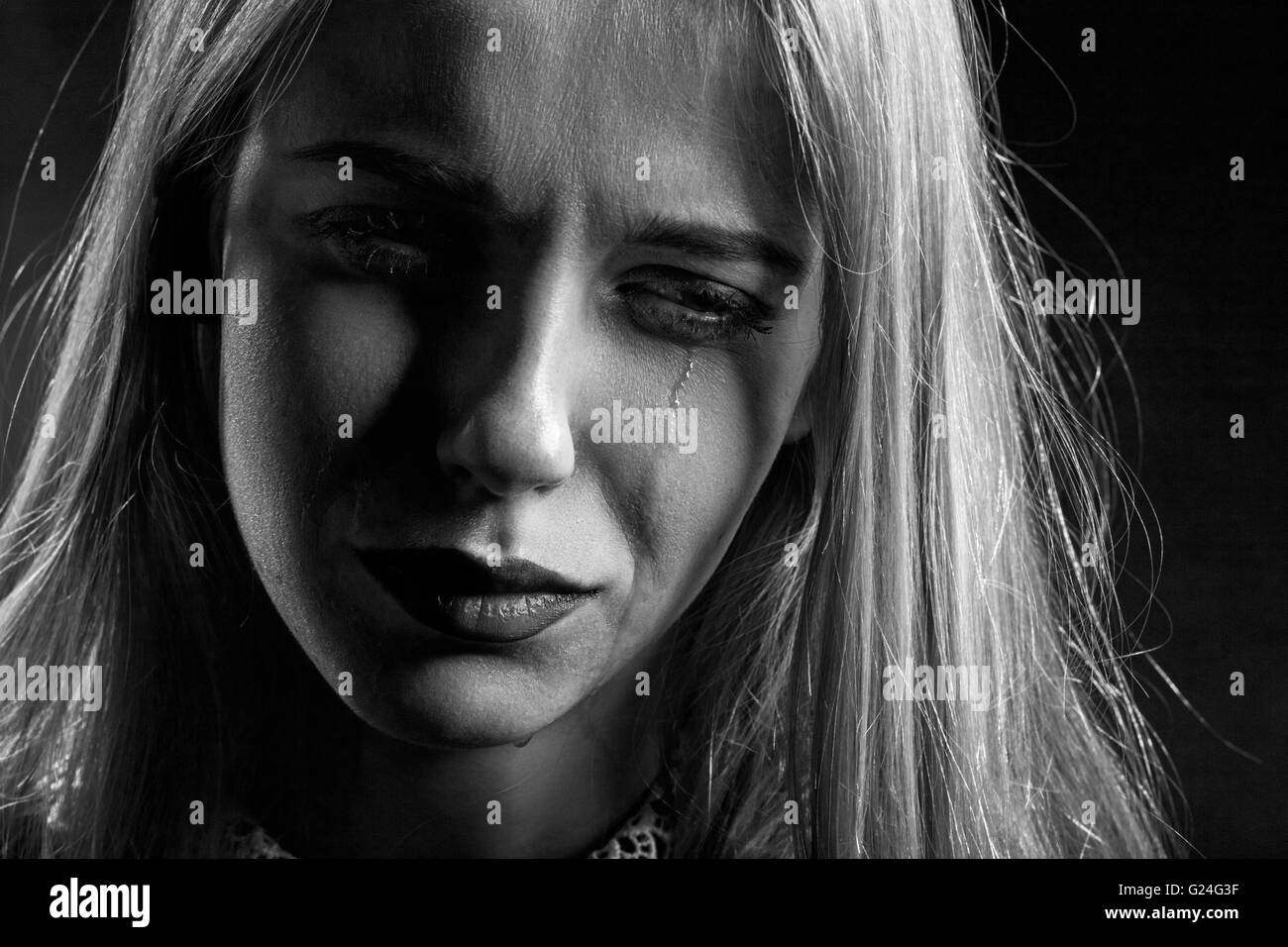 sad woman crying on black background, monochrome Stock Photo