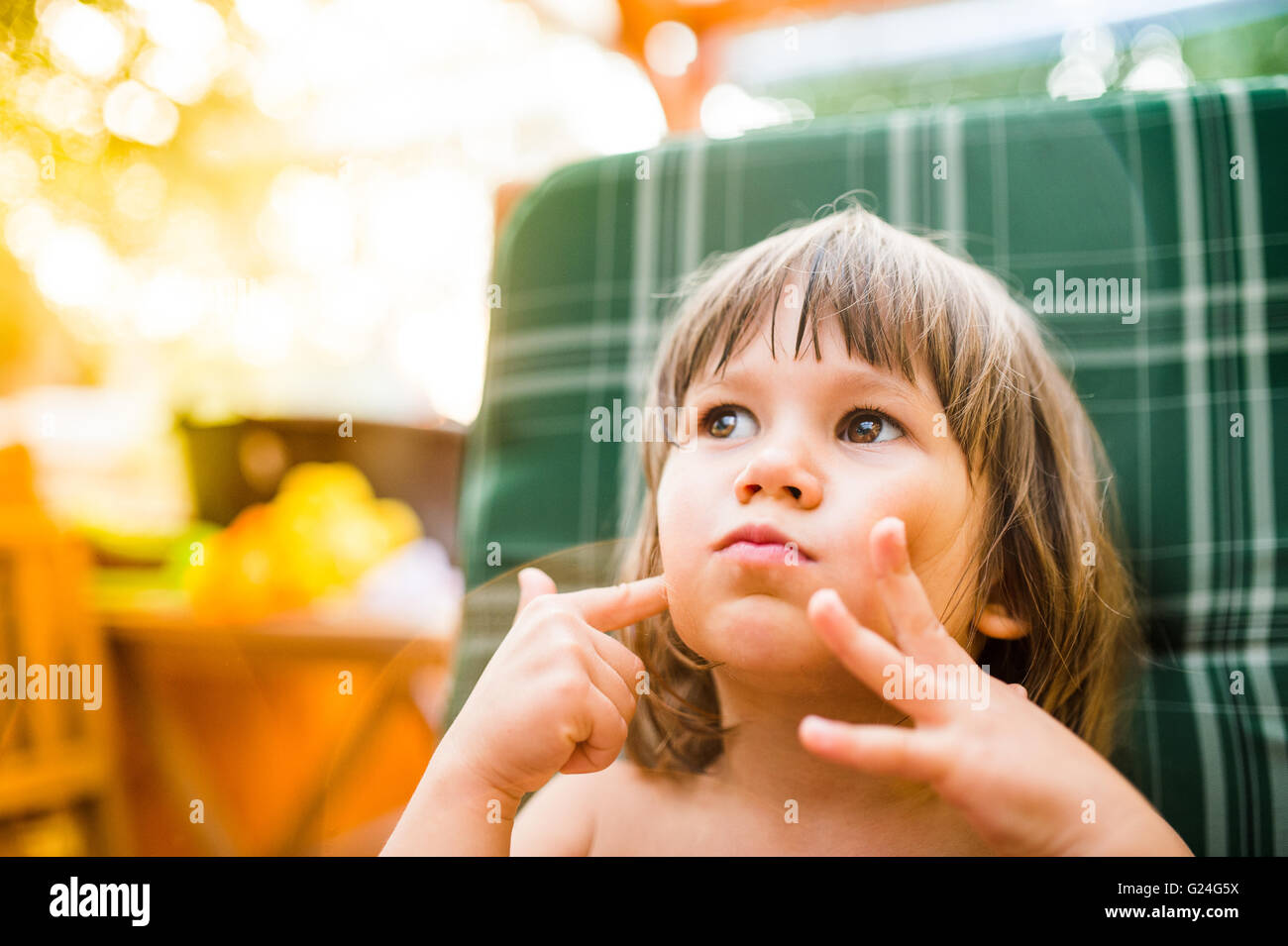 Cute little girl outside in garden holding her cheeks Stock Photo - Alamy