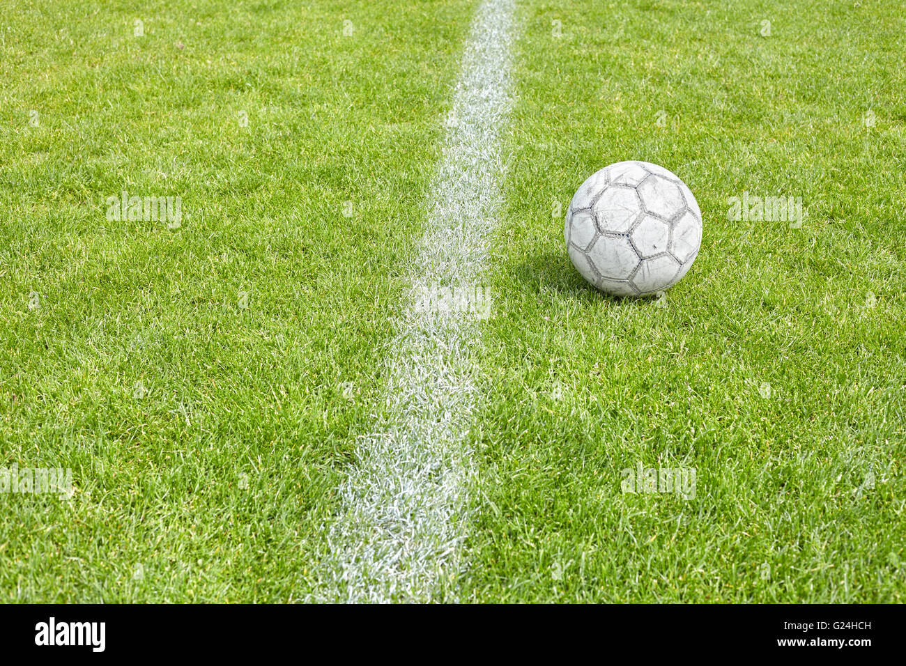 Used soccer ball on grass by a sideline, space for text, shallow depth of field. Stock Photo