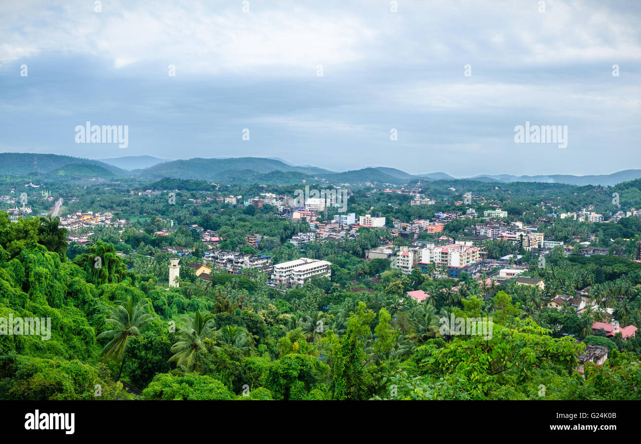 Ponda city embedded in beautiful lush green landscape with dark monsoon clouds over it. Stock Photo
