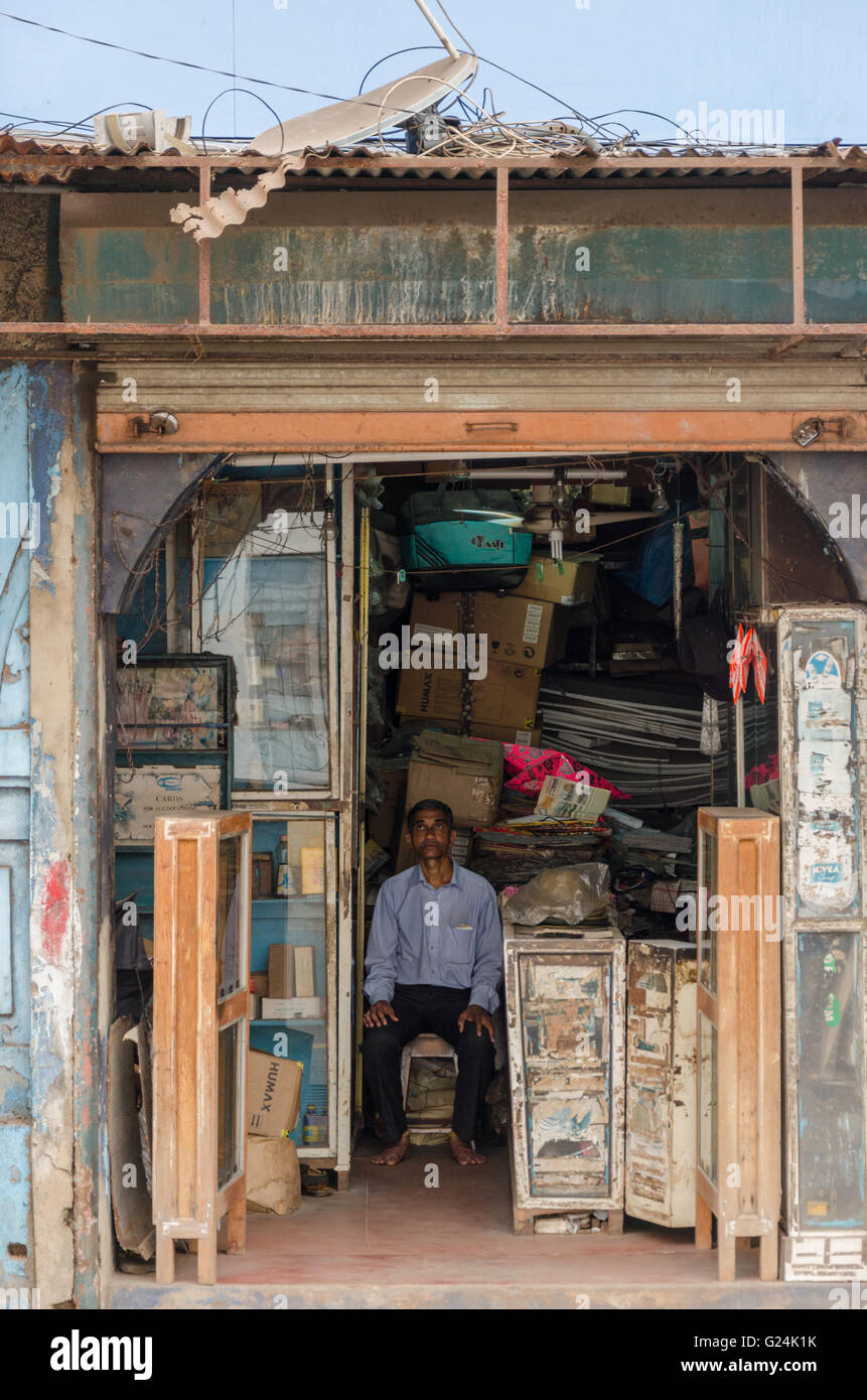 An old shop keeper sits on a stool inside his store on MG Road, Panjim, Goa, India Stock Photo