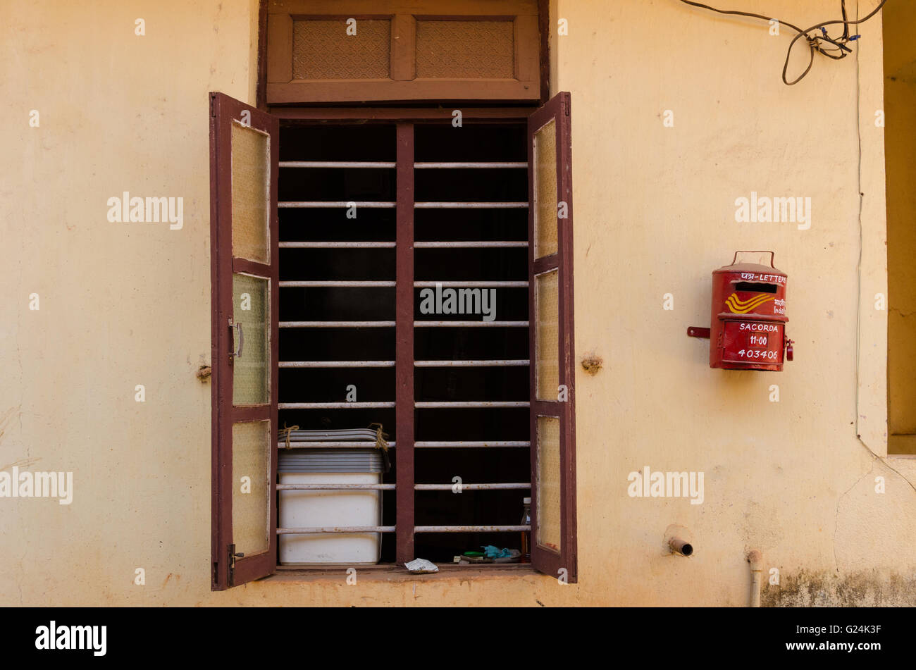 A tiny post box on wall besides a window of Sancorda Panchayat building, Goa, India Stock Photo