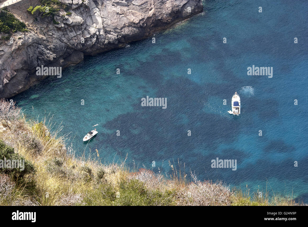 a beautiful picture of a harbour from a high viewpoint with 2 small boats, vegetation and rocks in Palma de Mallorca, Spain Stock Photo