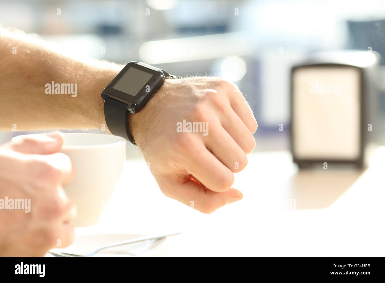 Close up of a man hand consulting a generic smartwatch on line and showing a blank screen taking a break in a coffee shop Stock Photo