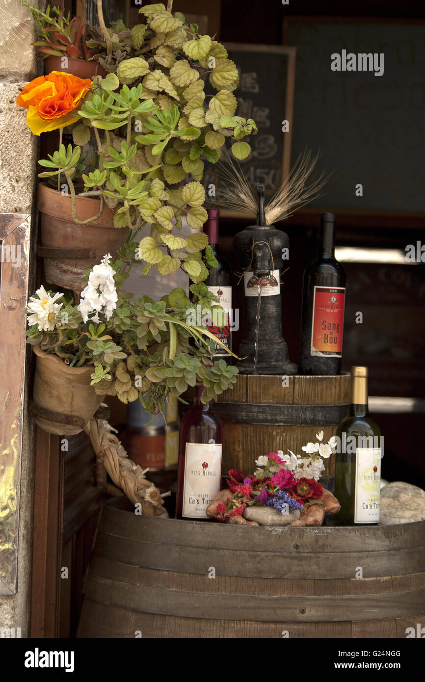 a beautiful picture of the entrance of a restaurant, wine bottles resting on a wooden barrel with flowers, Palma de Mallorca Stock Photo