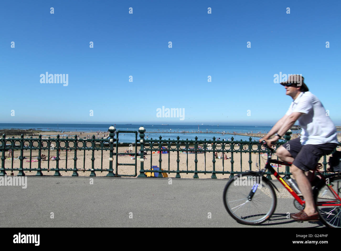 Cyclist on the promenade and people enjoying the sunshine on a sunny day at Margate beach in Kent, England Stock Photo