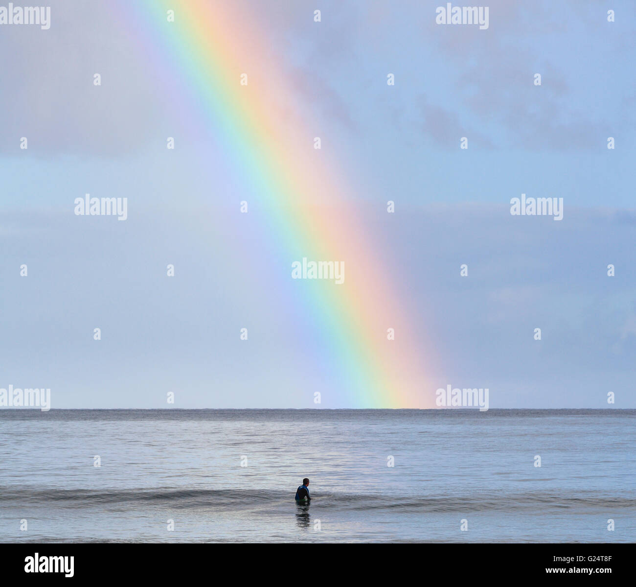 Surfer in Hanalei Bay sees rainbow Stock Photo