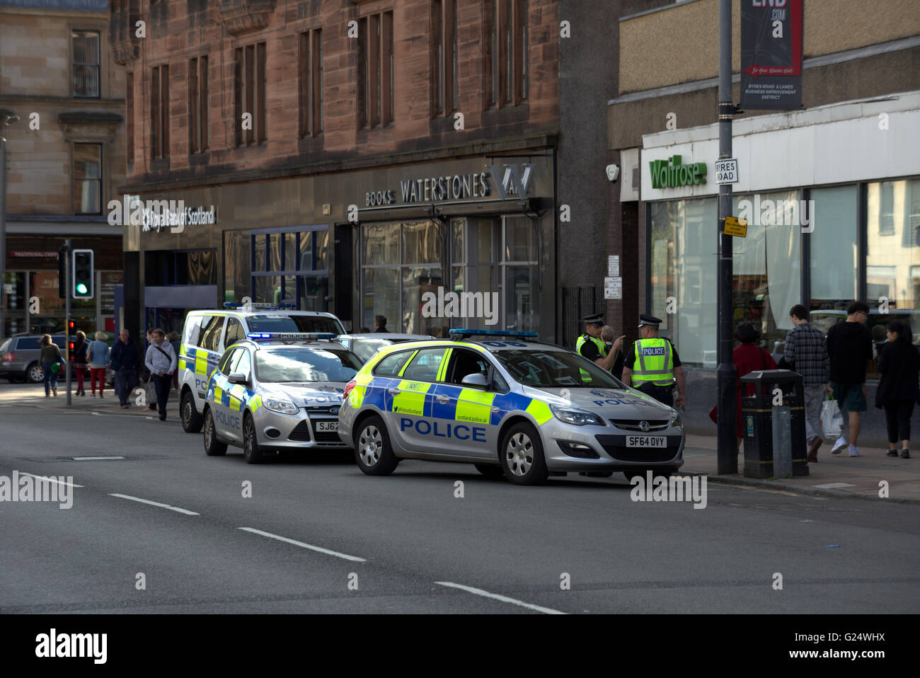 Police on patrol  three police vehicles investigate an incident in west end of Glasgow, Scotland, UK. Stock Photo