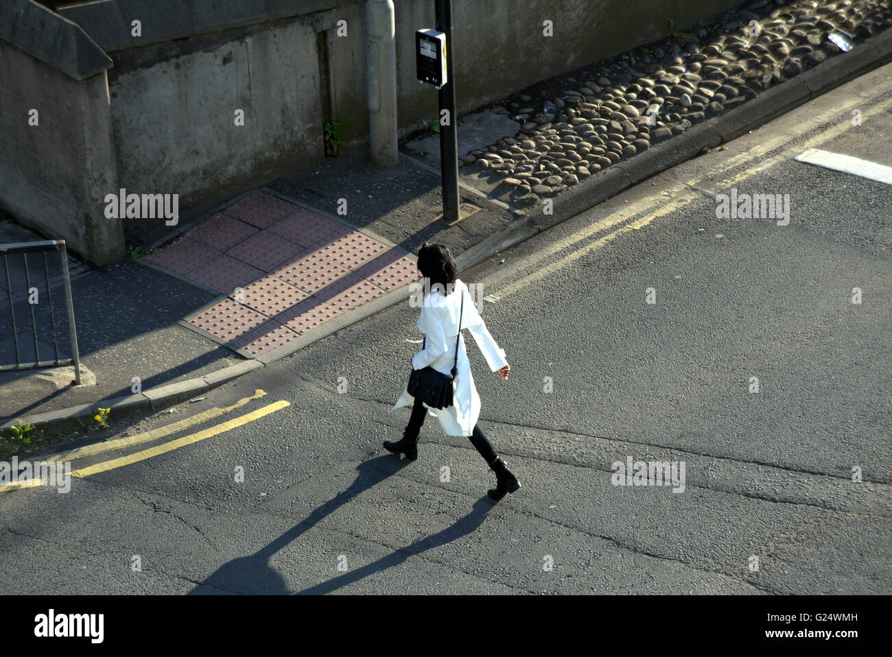 Woman  or fashionably dressed young girl walking at traffic lights viewed from above, Glasgow, Scotland, UK. Stock Photo