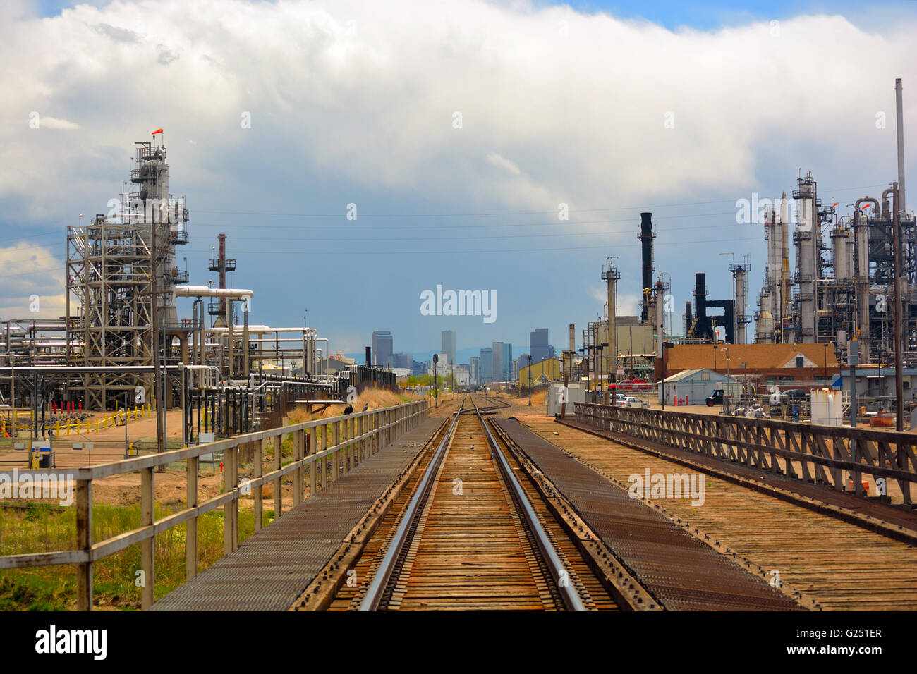 Oil and Gas Refinery Distillation Towers with Railroad Tracks and a Distant City Stock Photo