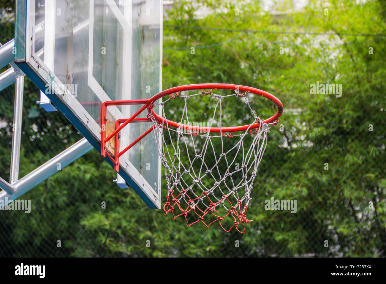Basketball hoop in the park with green trees as background. Stock Photo
