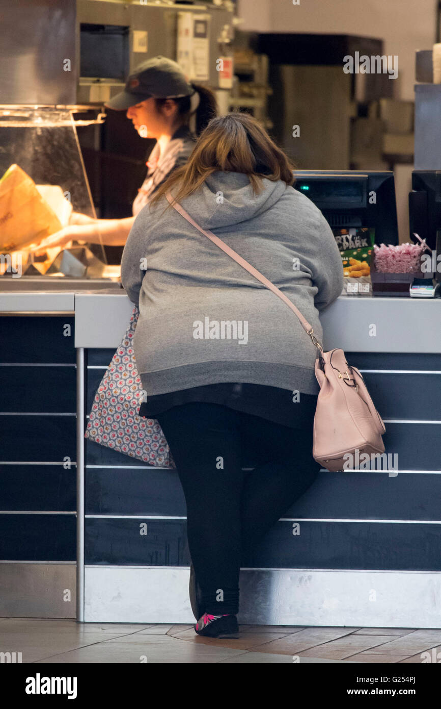 Obese overweight woman ordering fast food in a take away restaurant. Stock Photo
