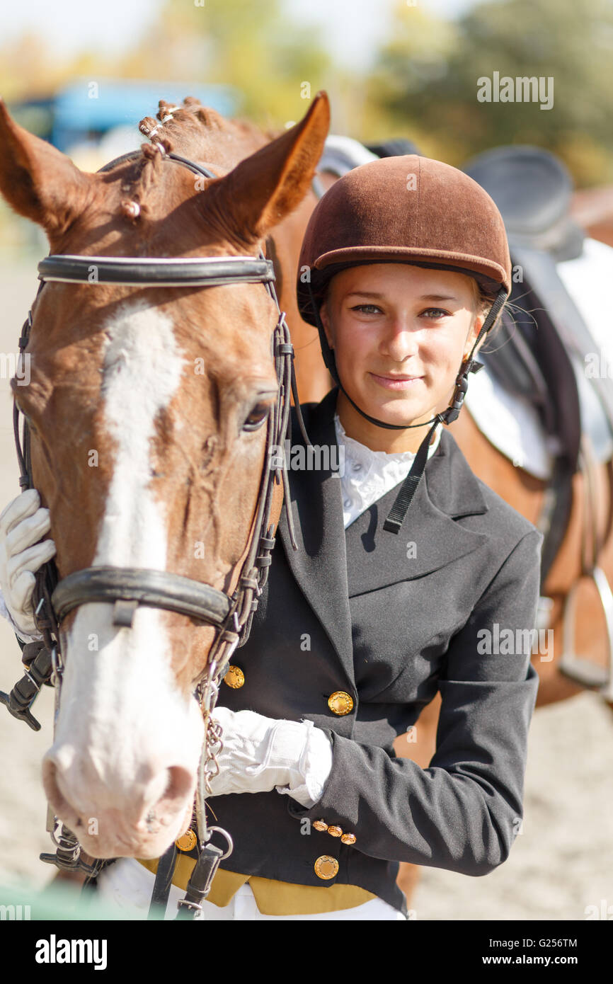 Young happy teenage rider girl with horse. Sportswoman equestrian portrait Stock Photo