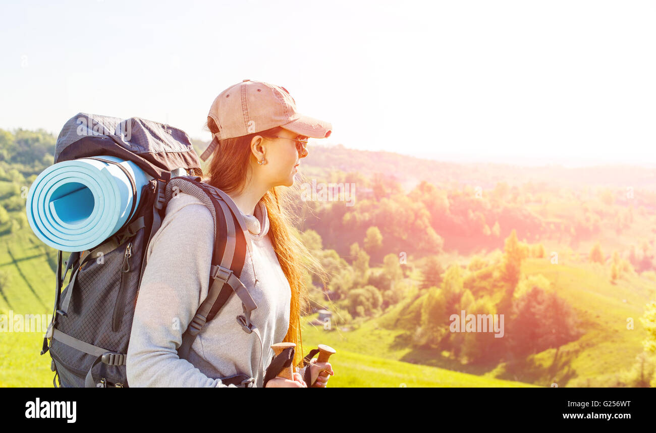 Young hiker woman with backpack walking in the mountains. Traveling vacation background with copy space Stock Photo