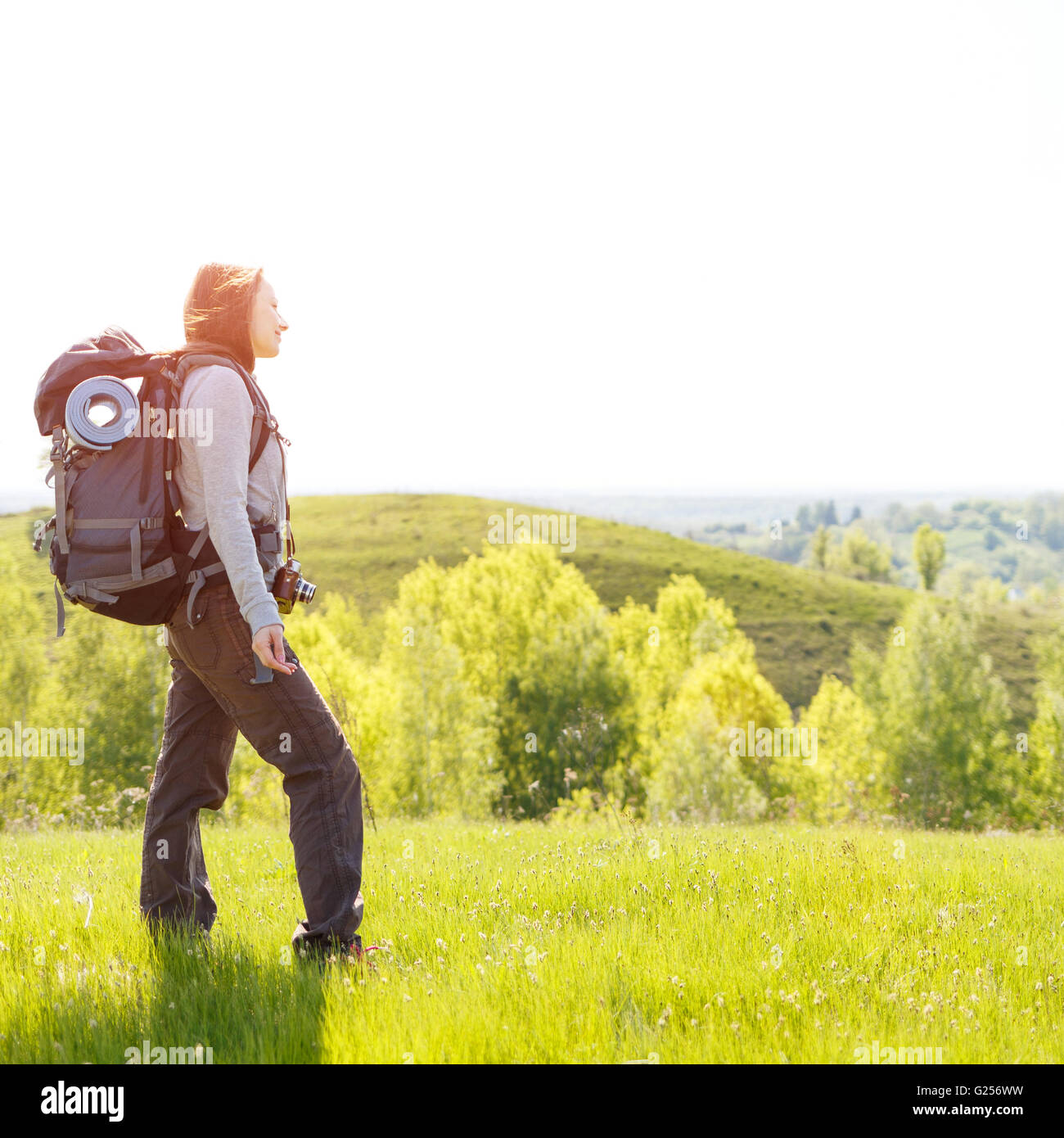 Young hiker woman with backpack standing on summit of hill. Happy girl ...