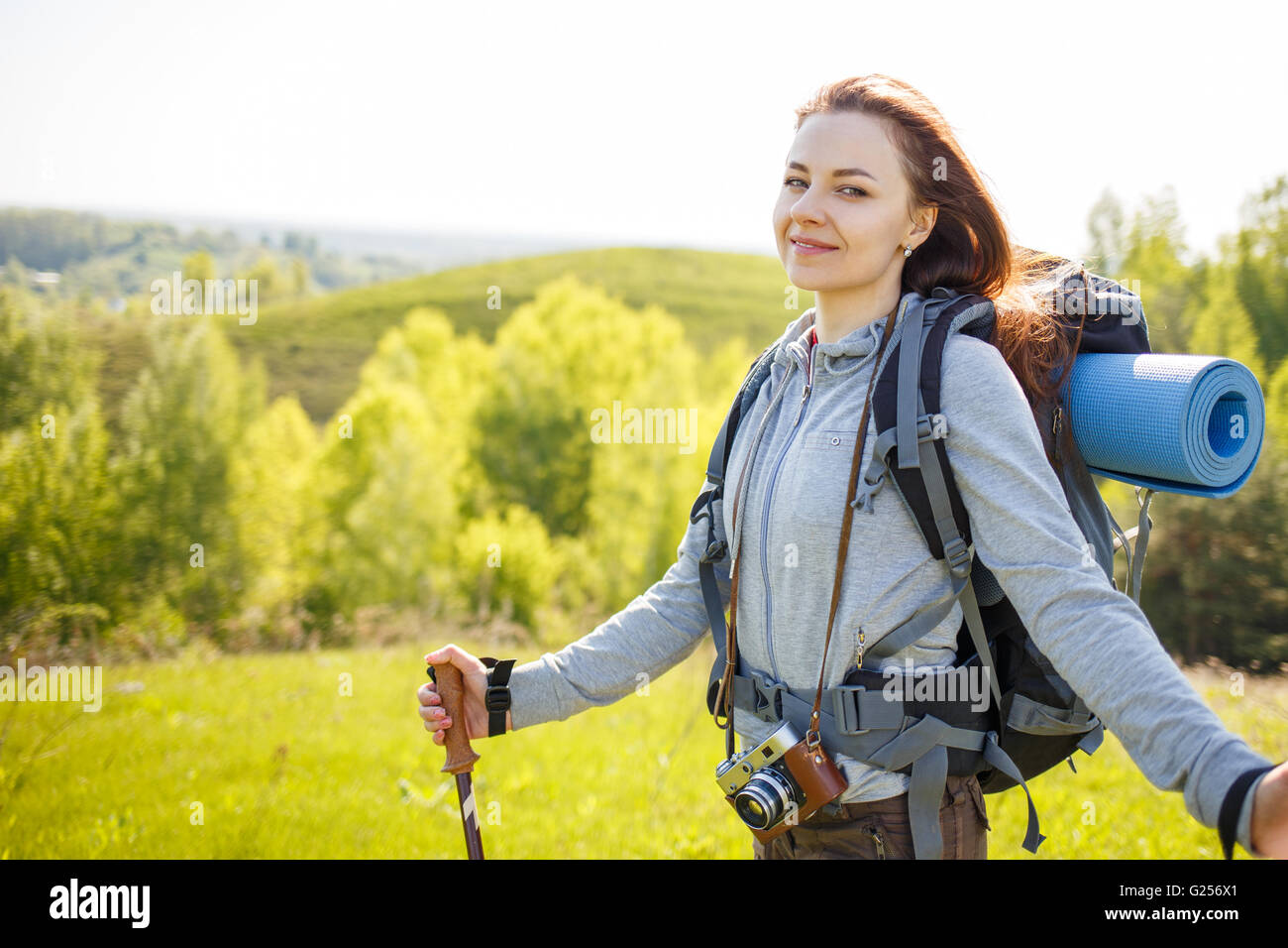 Young hiker woman with backpack standing on summit of hill. Happy girl ...