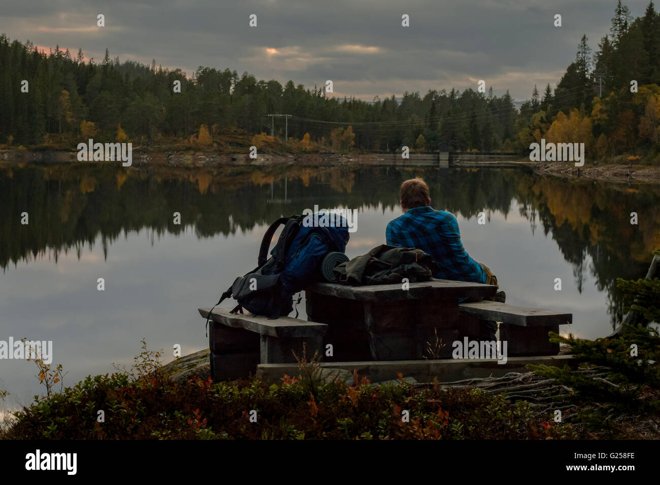 Hiker resting on bench by a lake Stock Photo
