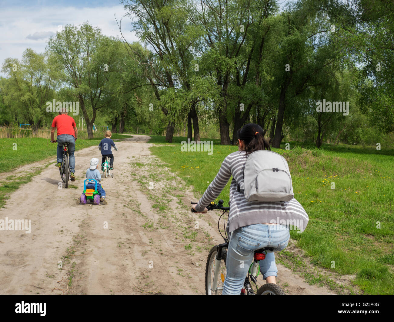 Family cycling along road in rural countryside Stock Photo