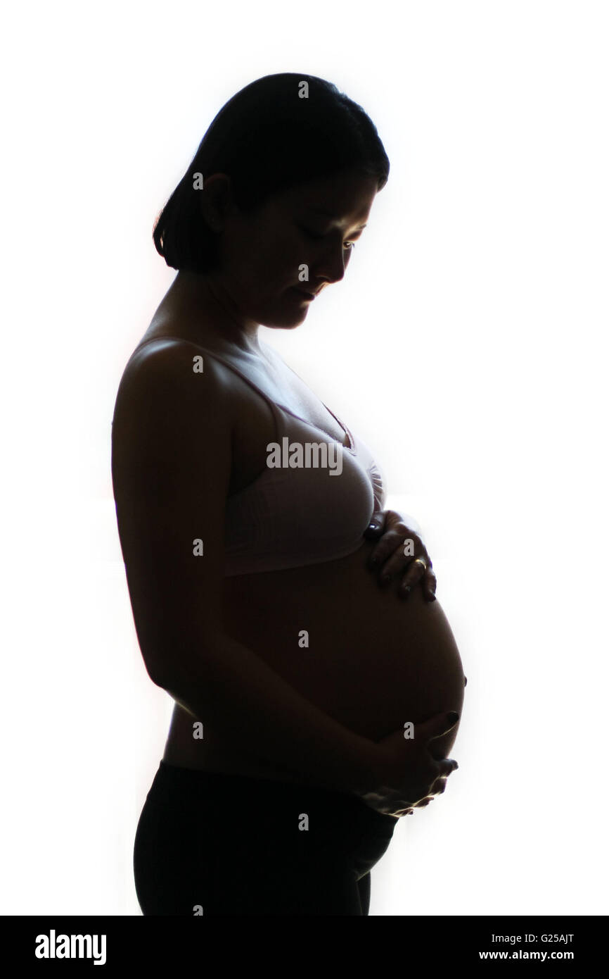 Silhouette of a pregnant woman holding belly Stock Photo