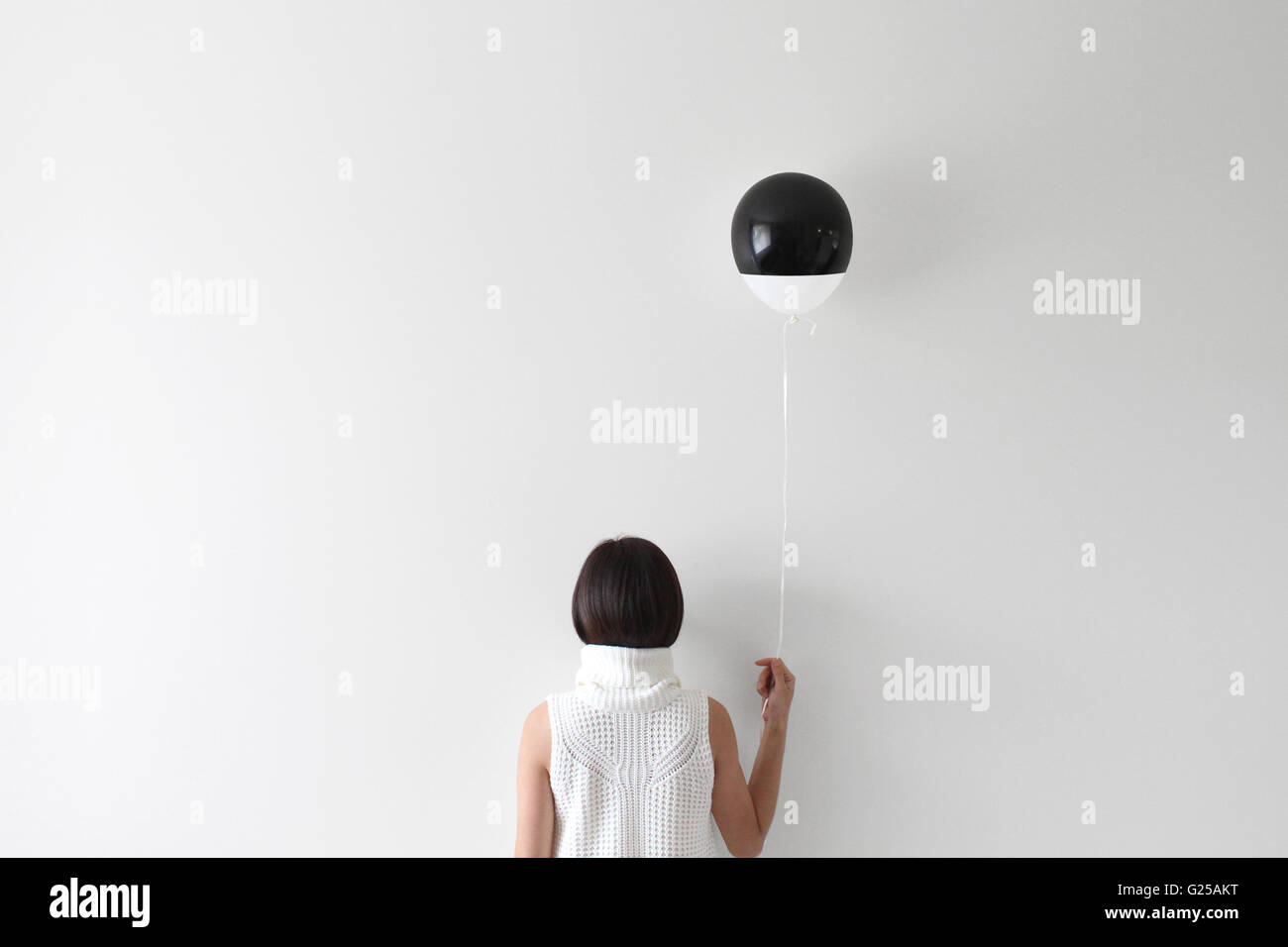 Rear view portrait of a woman facing wall holding balloon Stock Photo