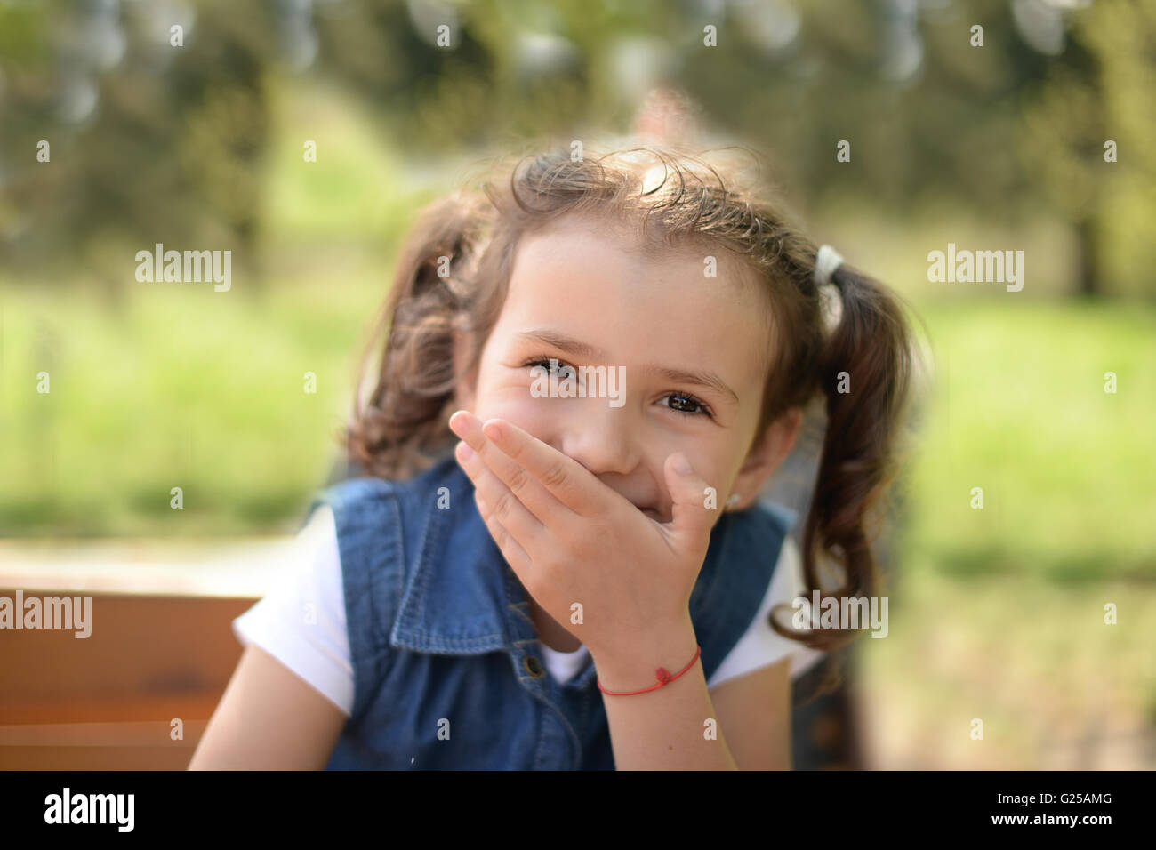 Portrait of Girl holding hand in front of her mouth laughing Stock Photo