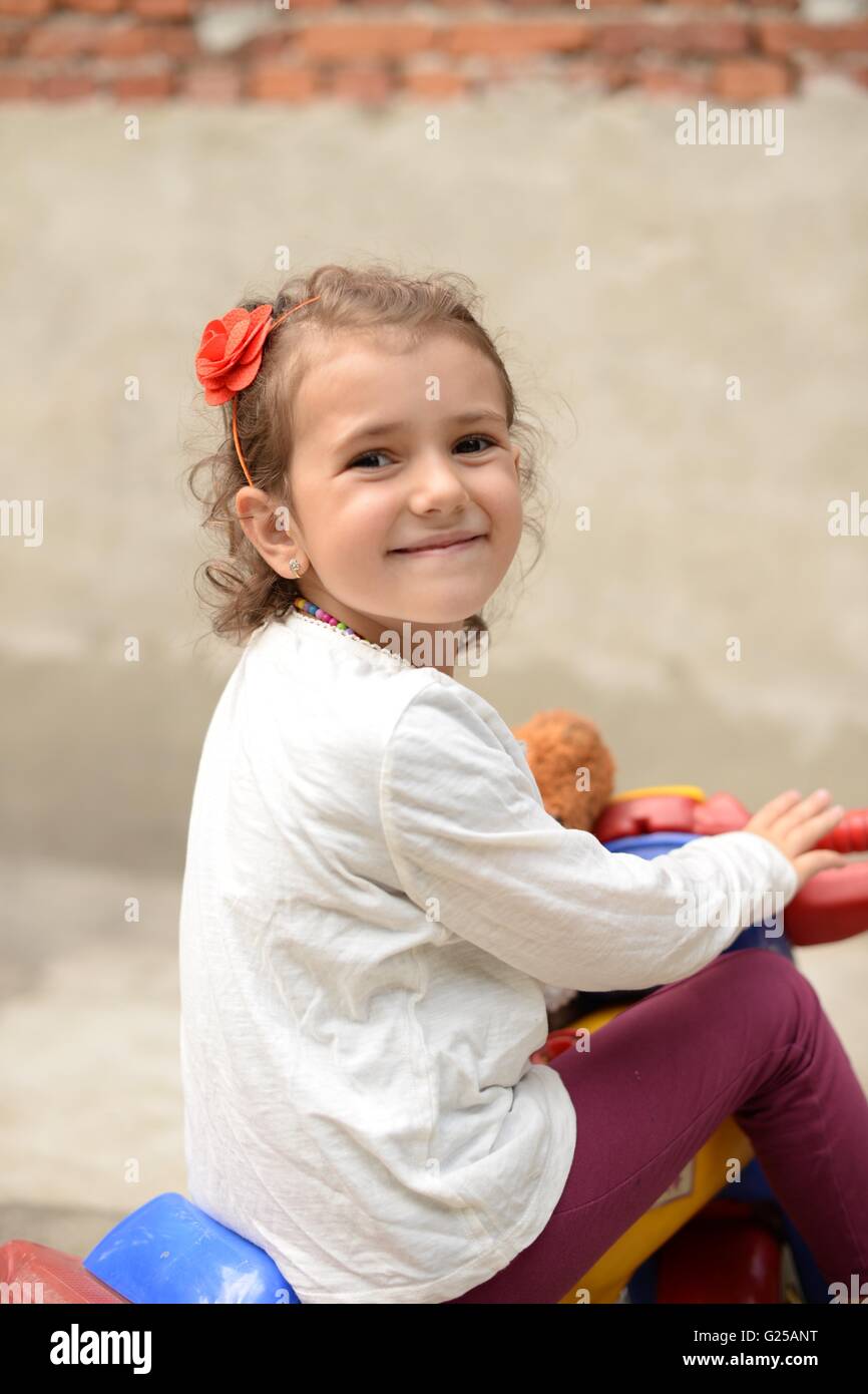 Girl sitting on plastic tricycle Stock Photo