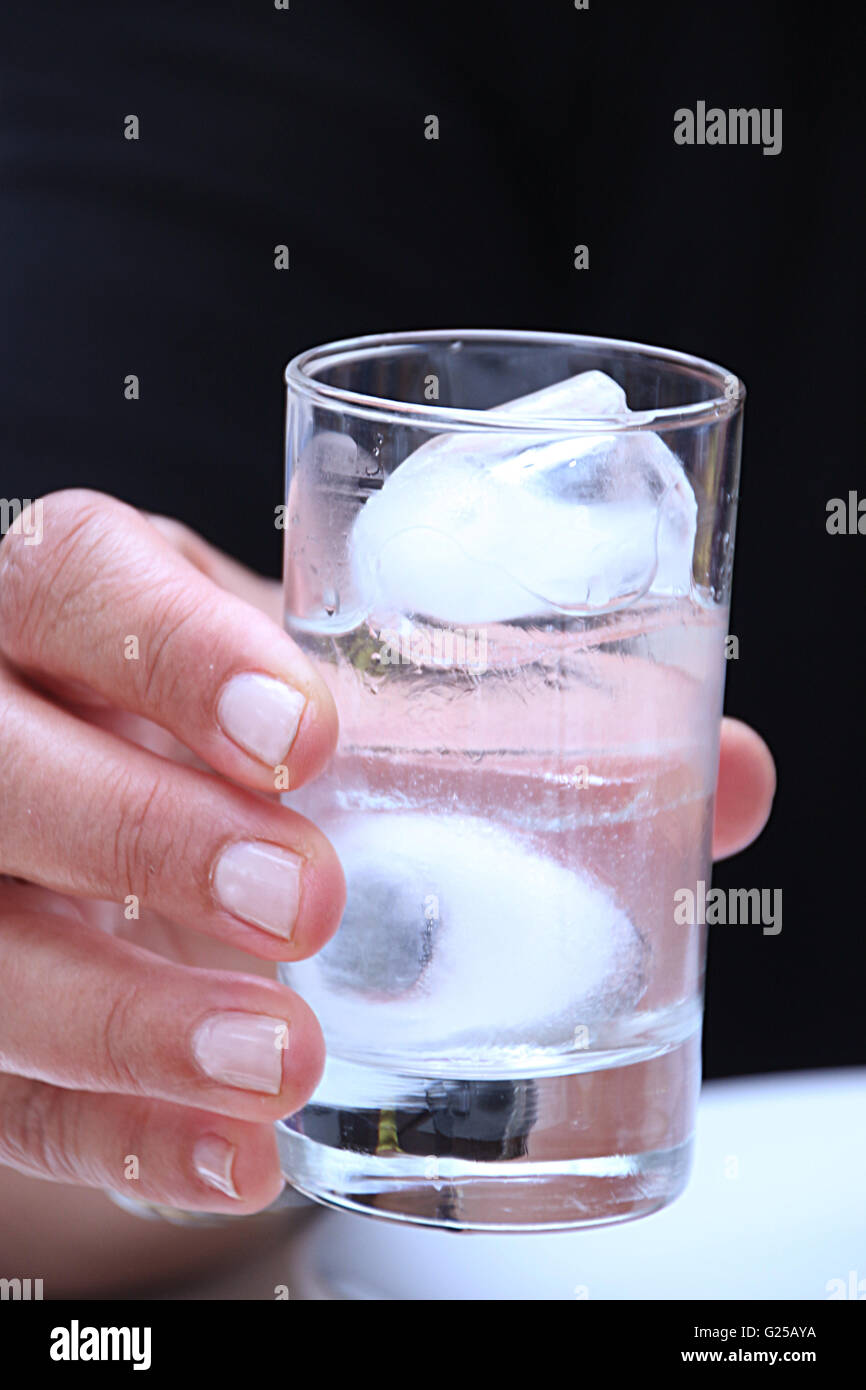 Woman holding a glass of ouzo with ice cubes Stock Photo