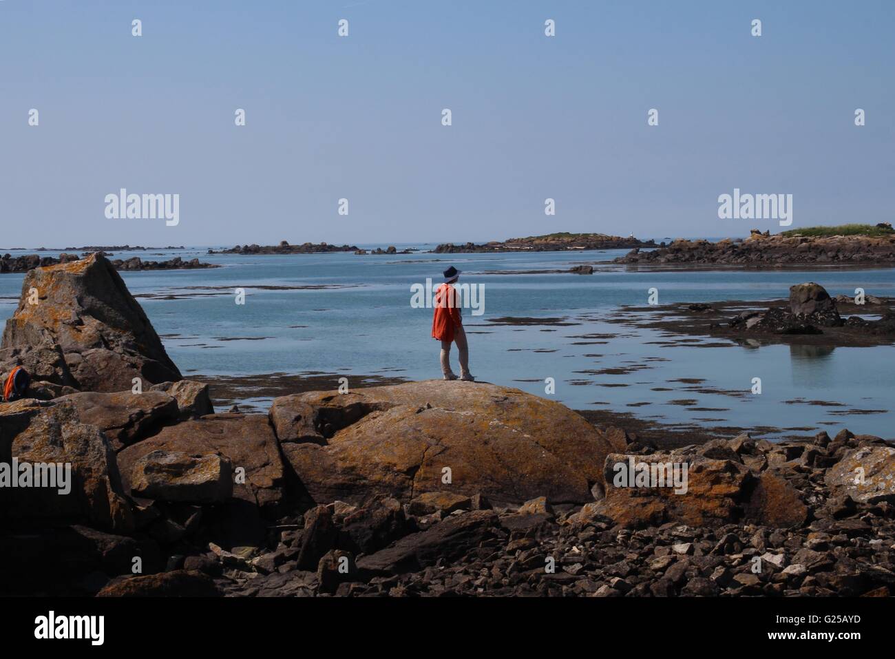 Woman standing on rocks, looking out to sea, Chausey, Normandy, France Stock Photo
