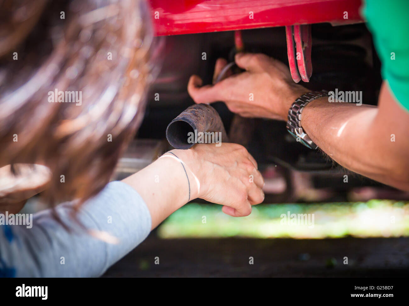 a do-it-yourselfer repairs his car. Man repairing his car. A man beneath his car does repair work. Stock Photo