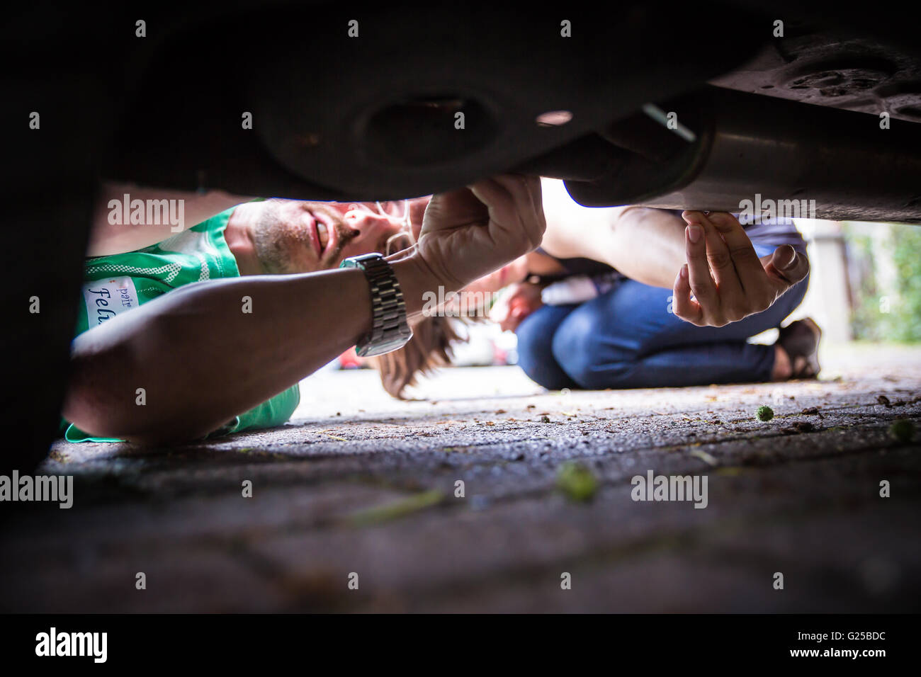 a do-it-yourselfer repairs his car. Man repairing his car. A man beneath his car does repair work. Stock Photo
