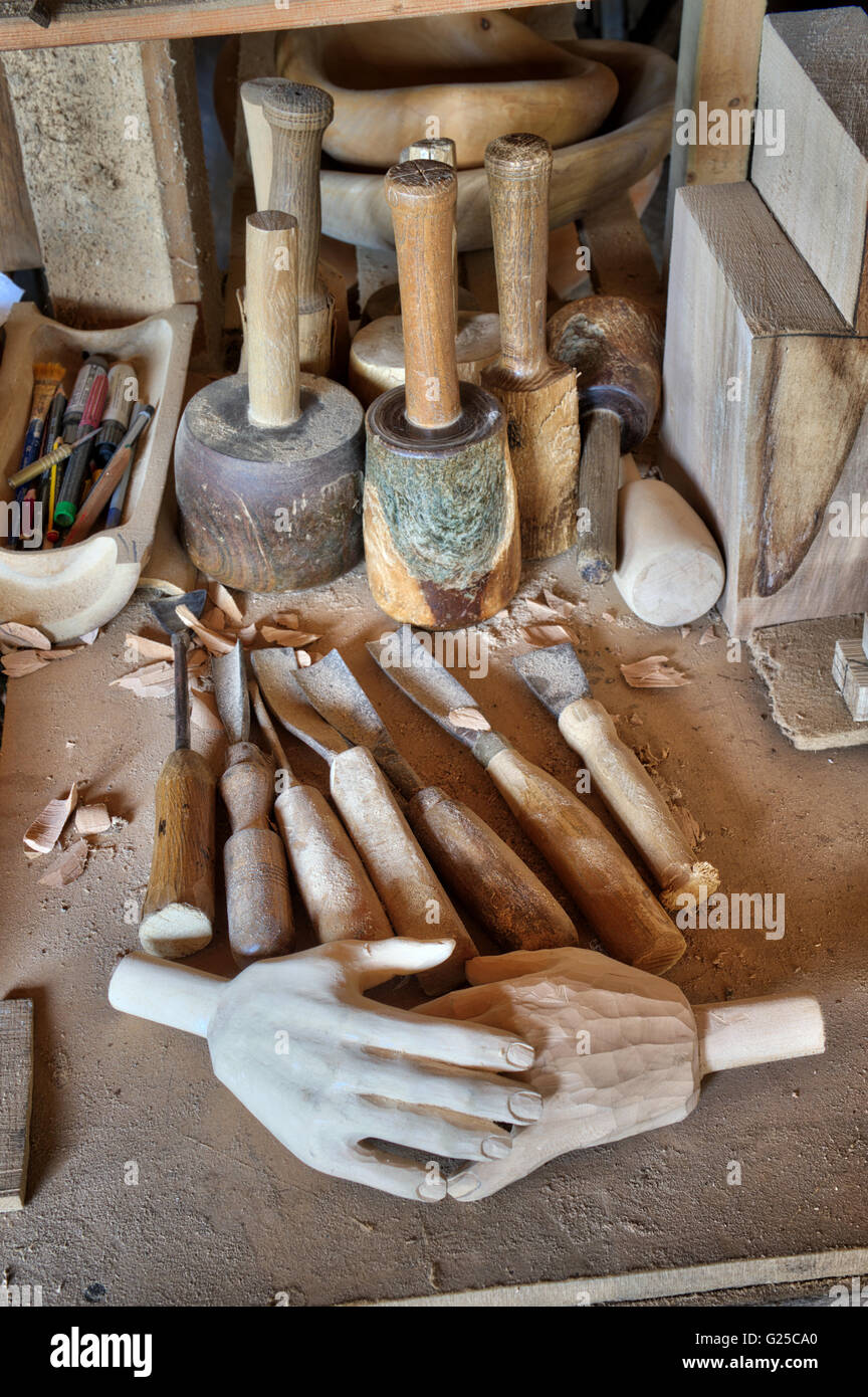 Carved wooden hands and chisels plus woodworking tools in a wood