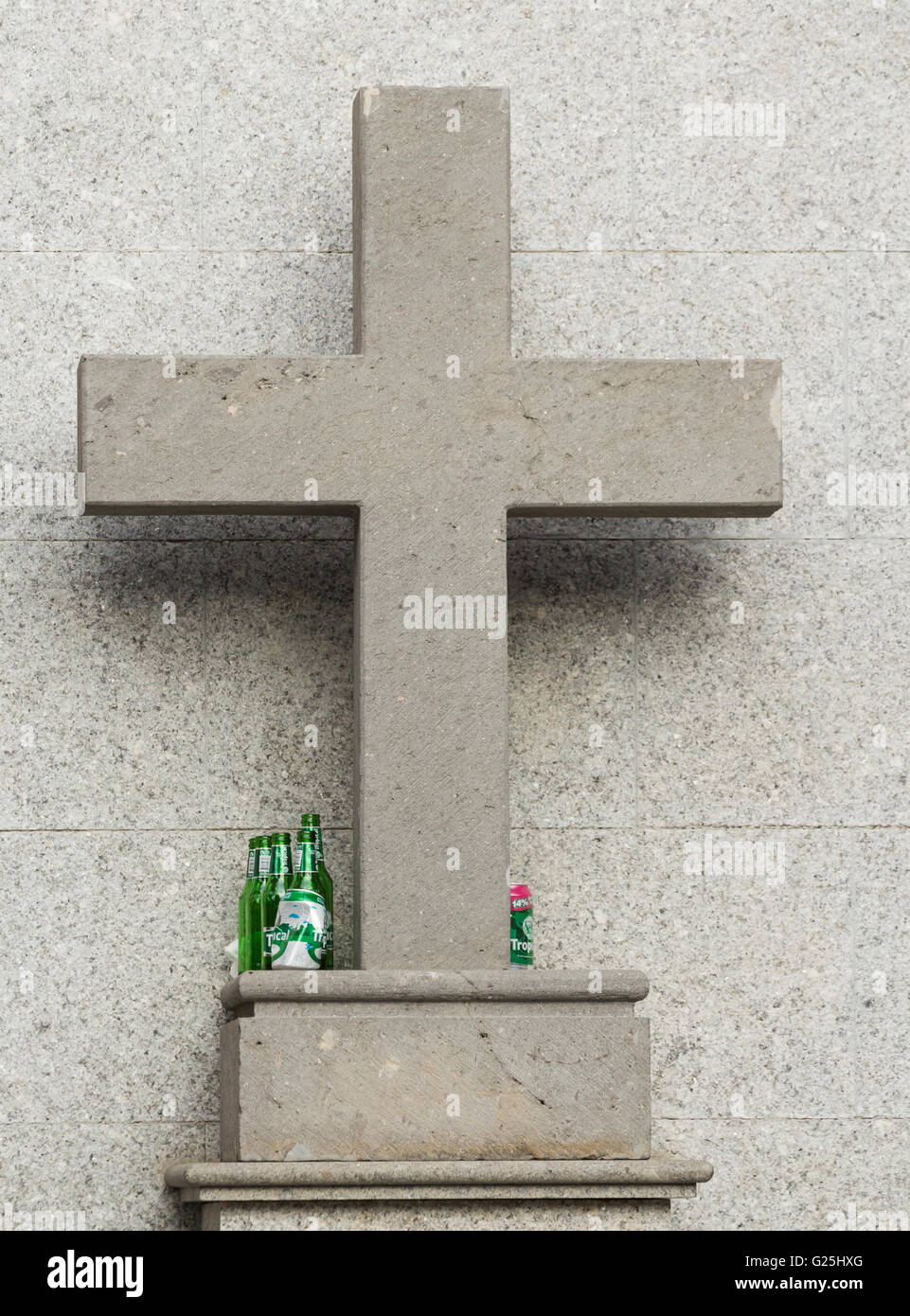 Empty beer bottles and cans on cross on religious statue in Spain Stock Photo