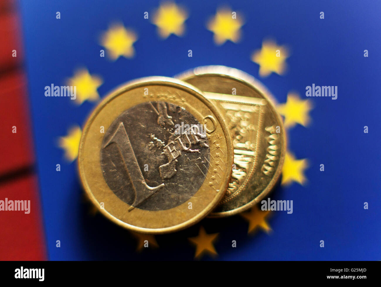 A 1 euro coin and a One Pound coin placed on a backdrop of The European flag, in London. Stock Photo