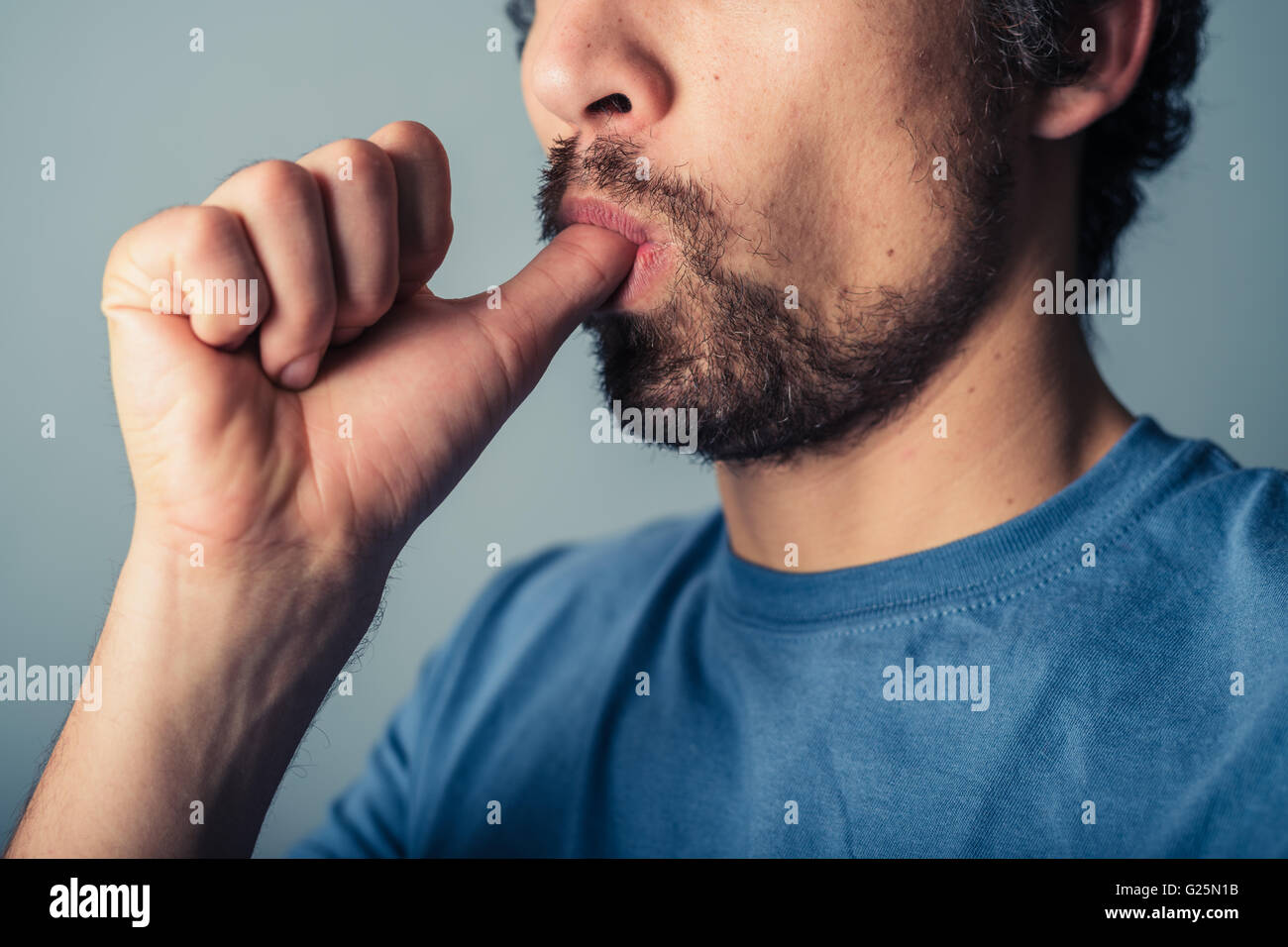 A silly young man is sucking his thumb Stock Photo