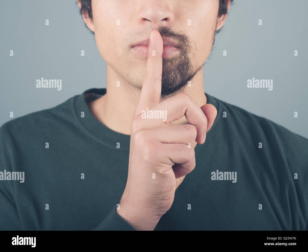 A man with a half shaved beard has his finger on his lips Stock Photo