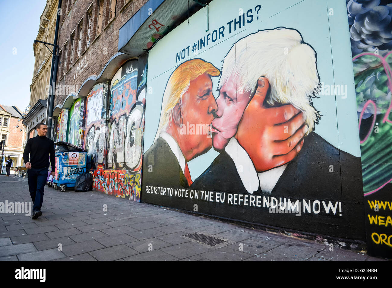 A man walks past a graffiti mural of Donald Trump and Boris Johnson kissing, which is sprayed on a disused building in the Stokes Croft area of Bristol. Stock Photo