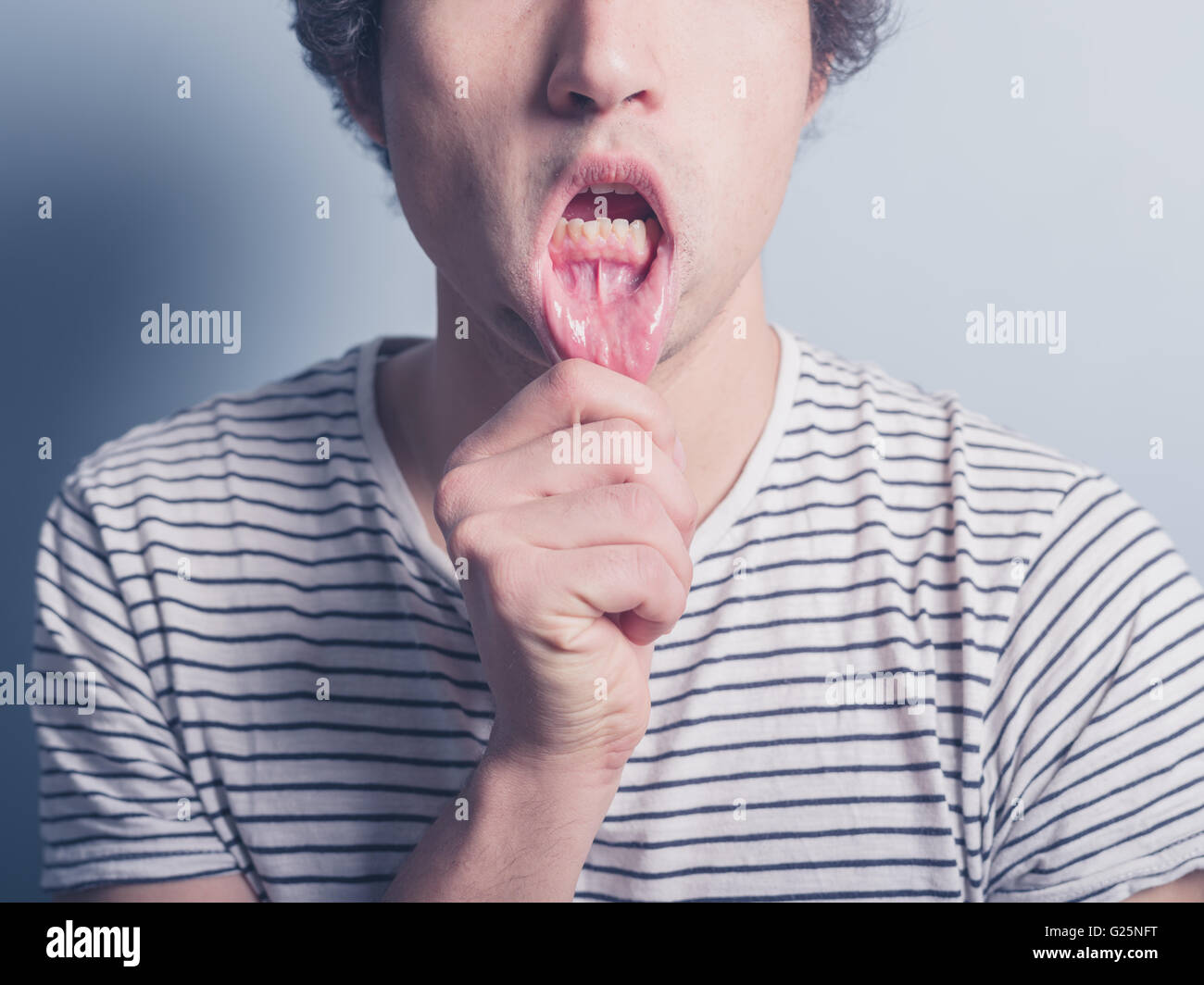 A young man is pulling his lower lip and is acting silly Stock Photo - Alamy