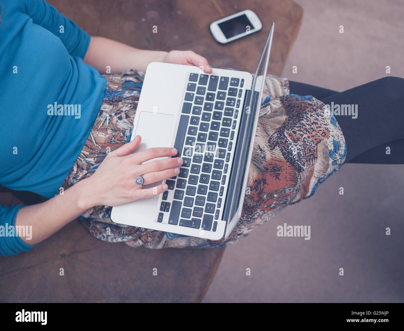 A young woman is sitting on a sofa at home in her living room and is ...