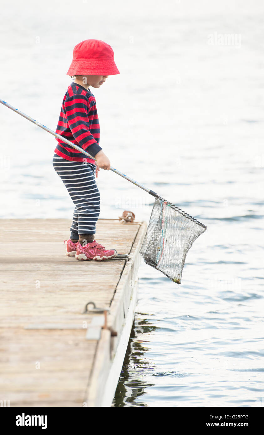 Child standing on dock by the sea with fishing net in hand, Stockholm,  Sweden Stock Photo - Alamy