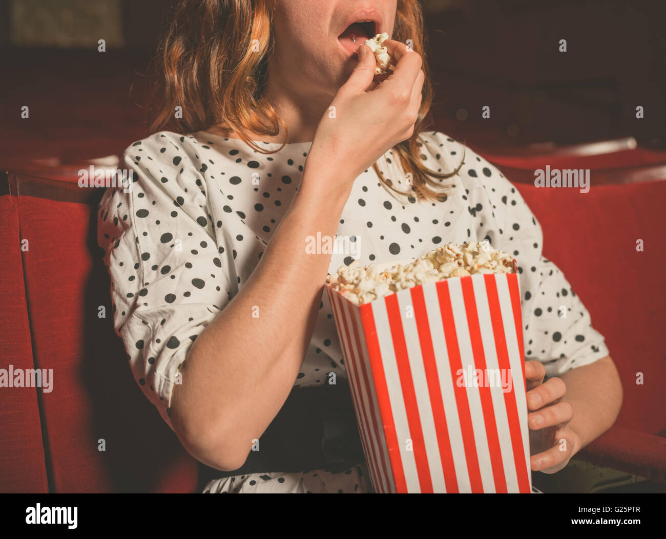 Closeup on a young woman eating popcorn in a movie theater Stock Photo