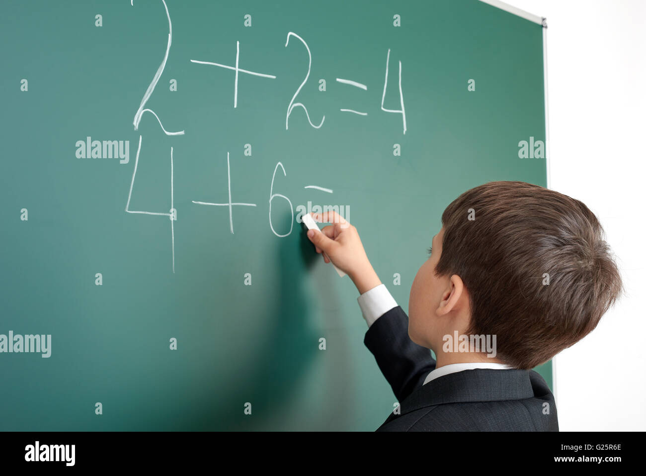 school boy decides examples math on chalkboard background, education exam concept Stock Photo