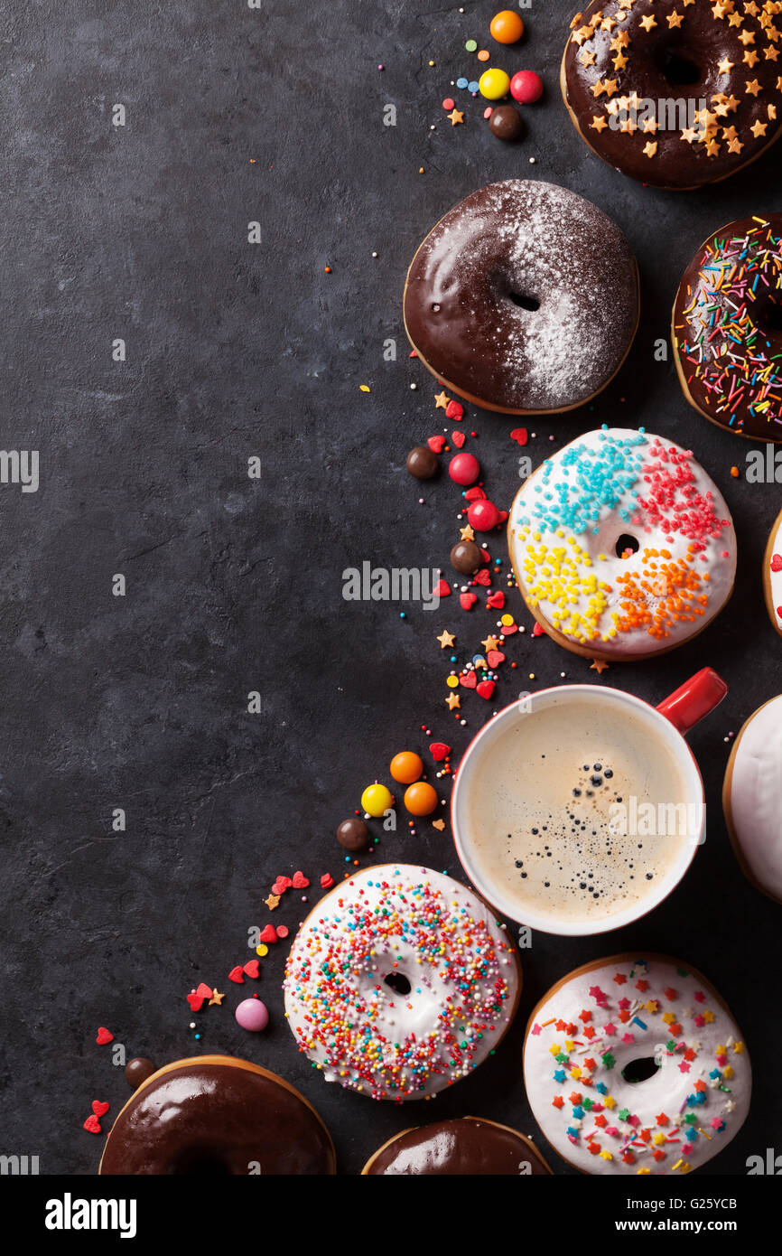 Colorful donuts and coffee on stone table. Top view with copy space ...