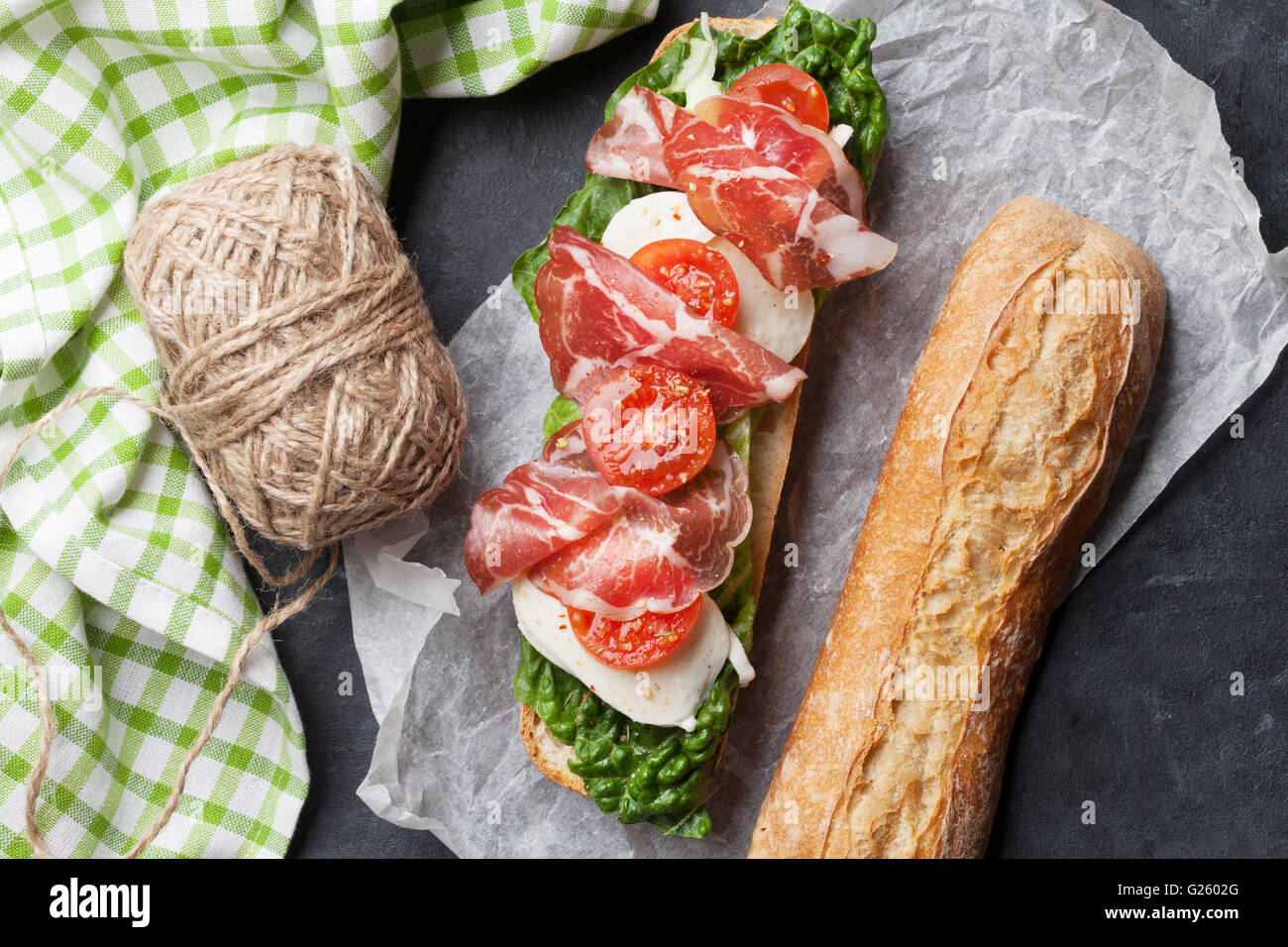 Ciabatta sandwich with romaine salad, prosciutto and mozzarella cheese over stone Stock Photo