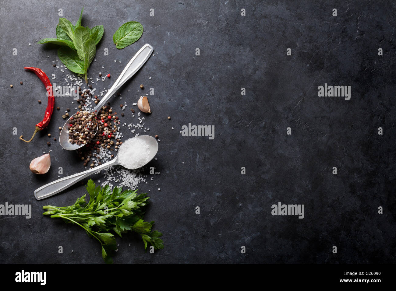 Black, white and red pepper and salt spices in spoon. Mint and parsley herbs. Top view with copy space Stock Photo