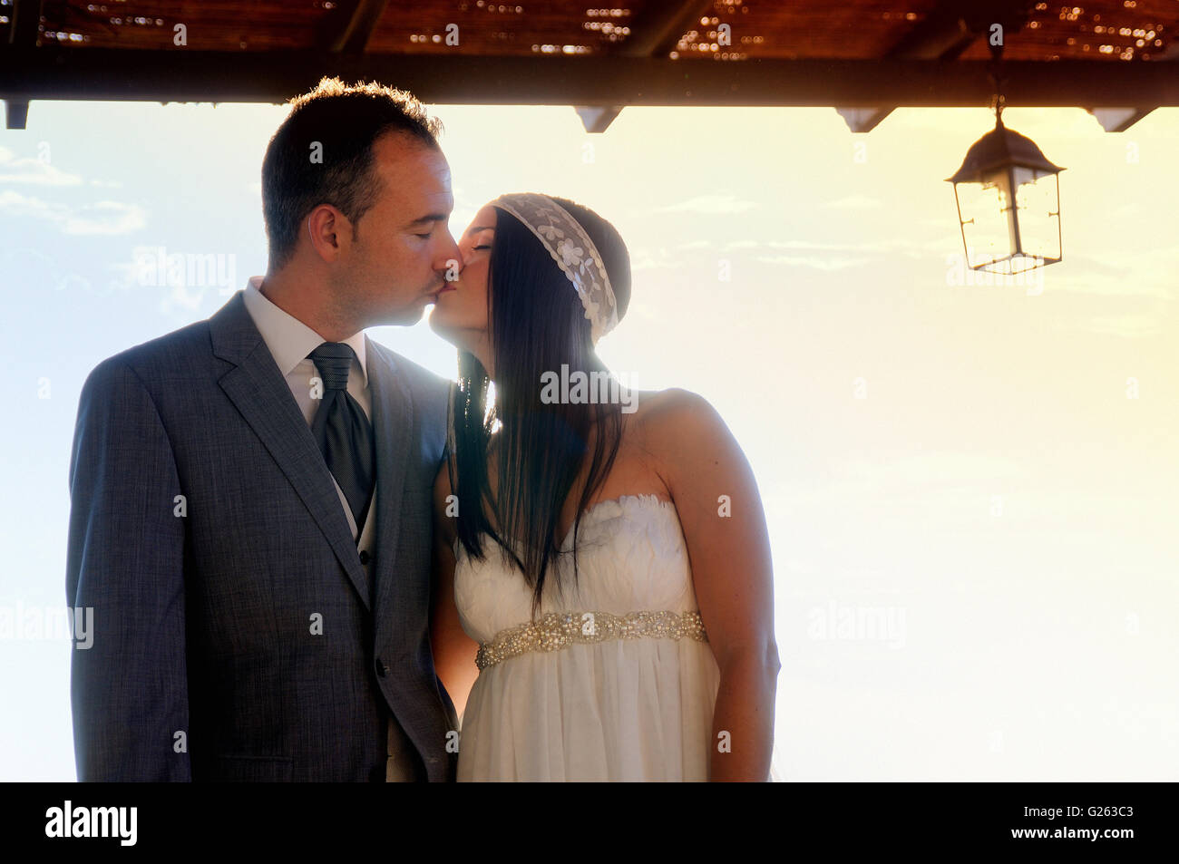 bride and groom kissing under a porch outdoors at sunset Stock Photo ...