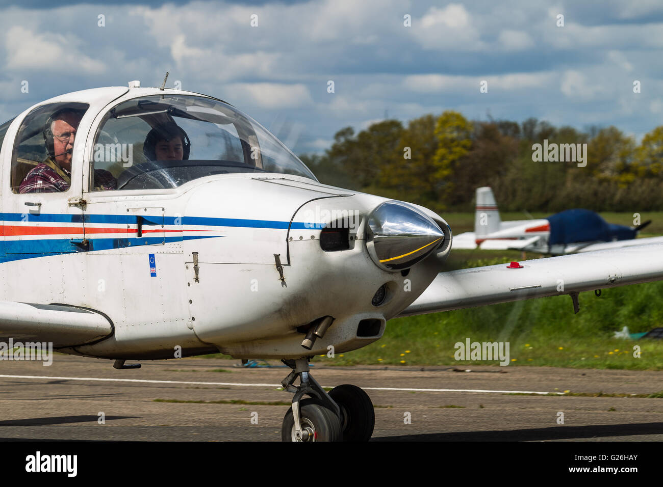 A Piper PA-38, G-BRHR taxis in after landing at Elstree Airfield in Hertfordshire, UK. Close-up of cockpit, engine and propeller Stock Photo