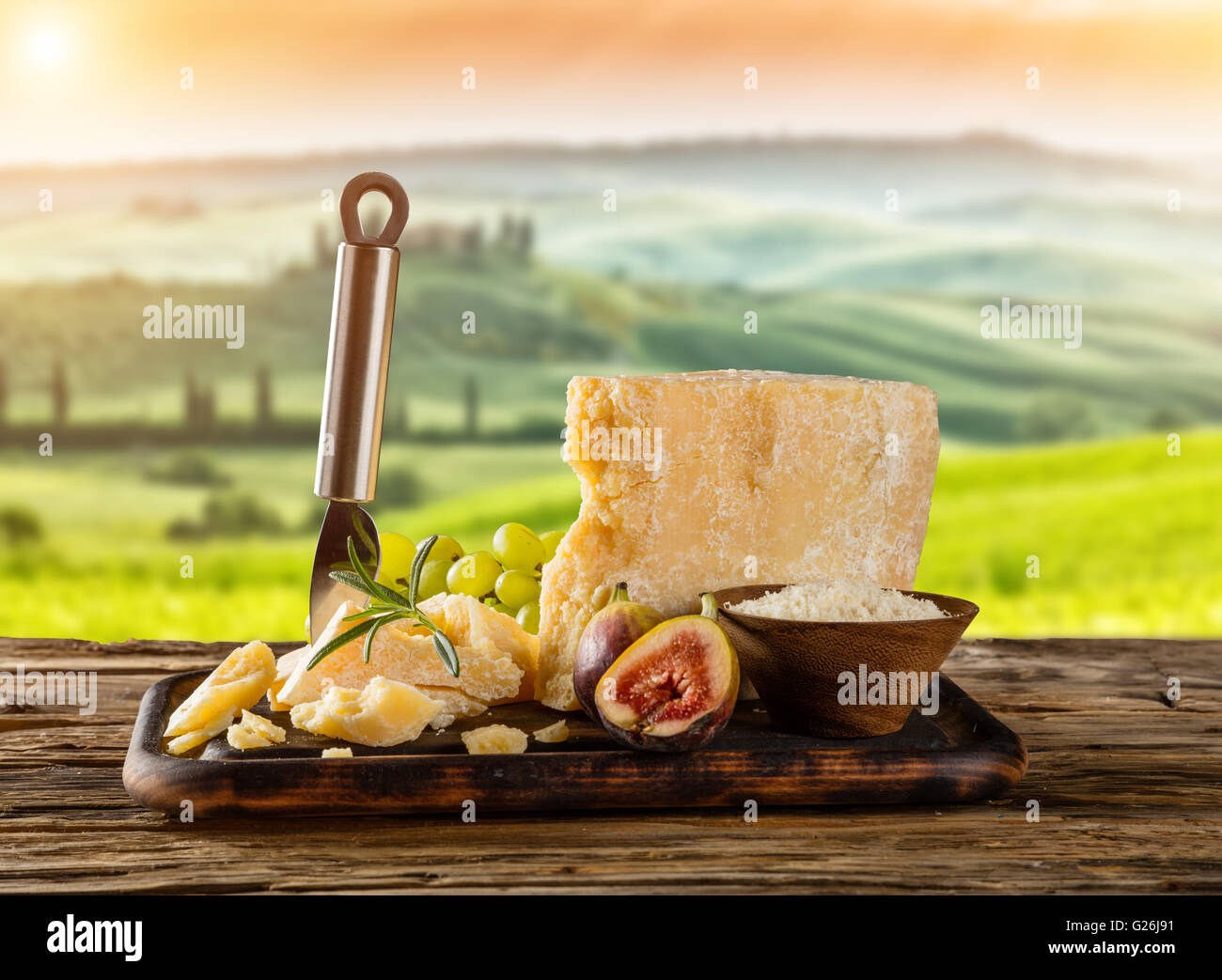 Parmesan cheese on cutting board placed on wood, blur countryside on background Stock Photo