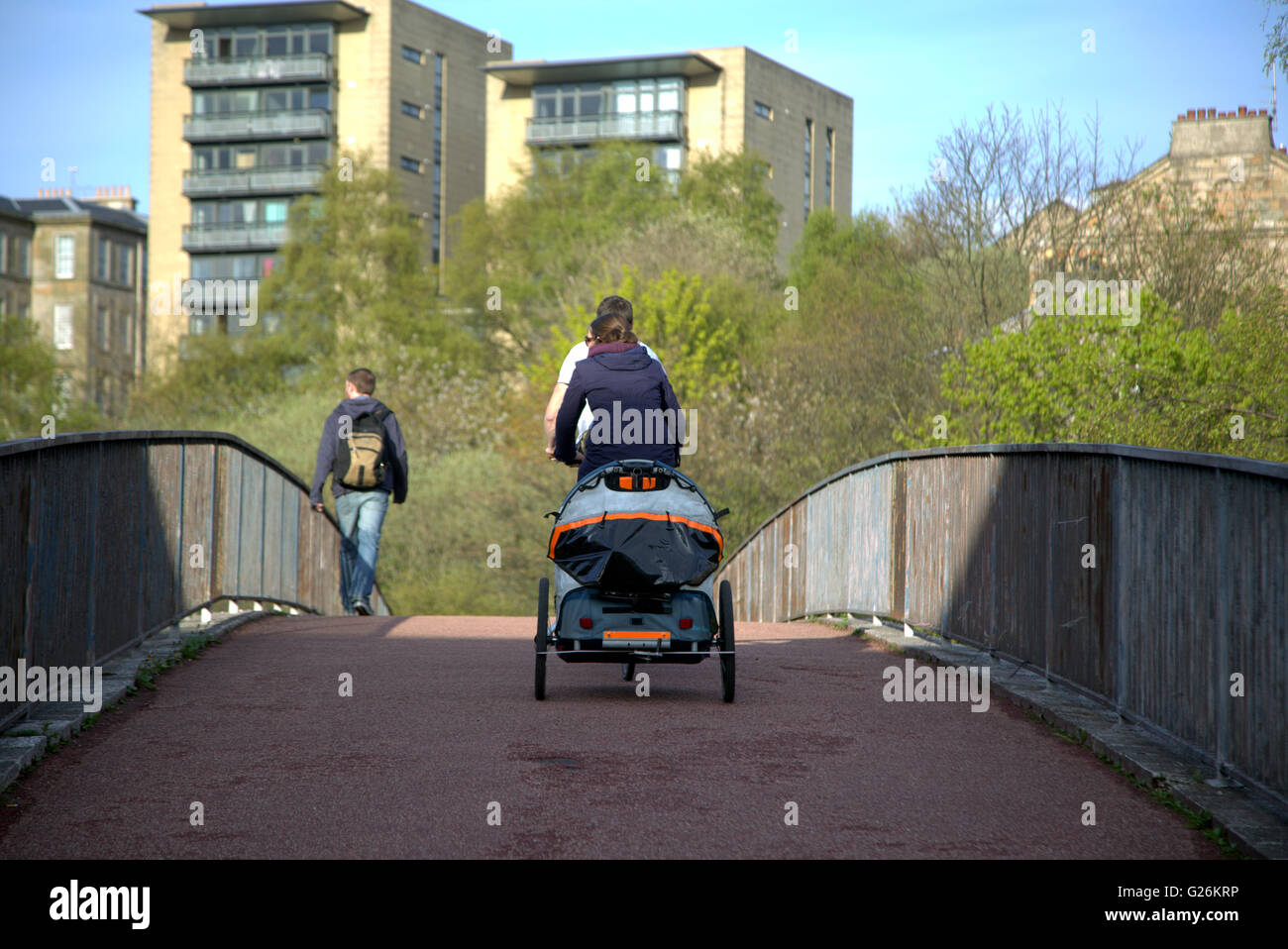 young couple on tandem pilling a child carrier in the city, Glasgow,in the city, Glasgow, Scotland, UK. Stock Photo