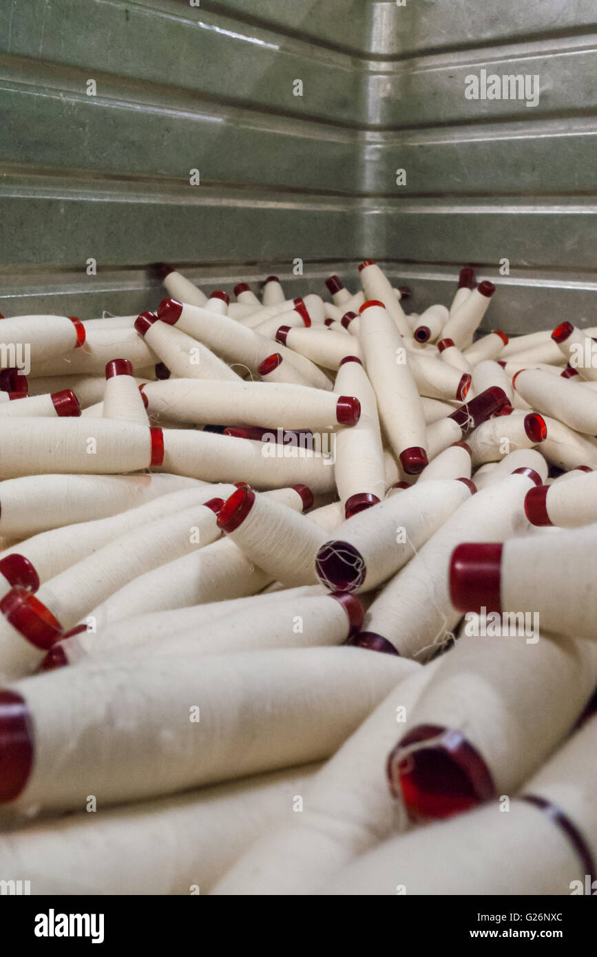 fresh textile yarn wrapped translucent red polymer bobbins collected