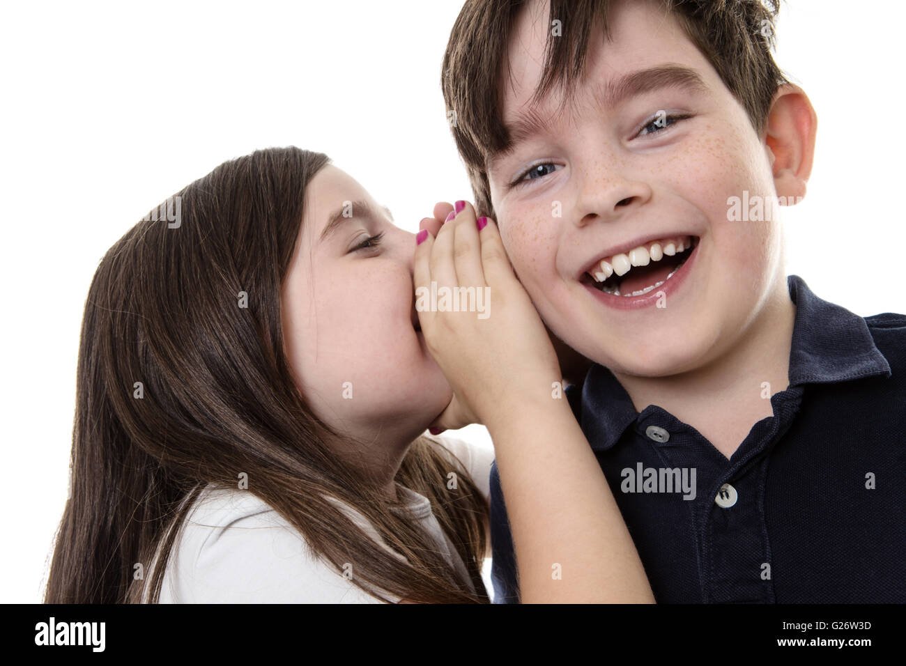 two children whispering into each others ear sharing a secret! Stock Photo